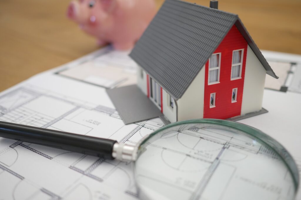 white and red wooden house beside grey framed magnifying glass