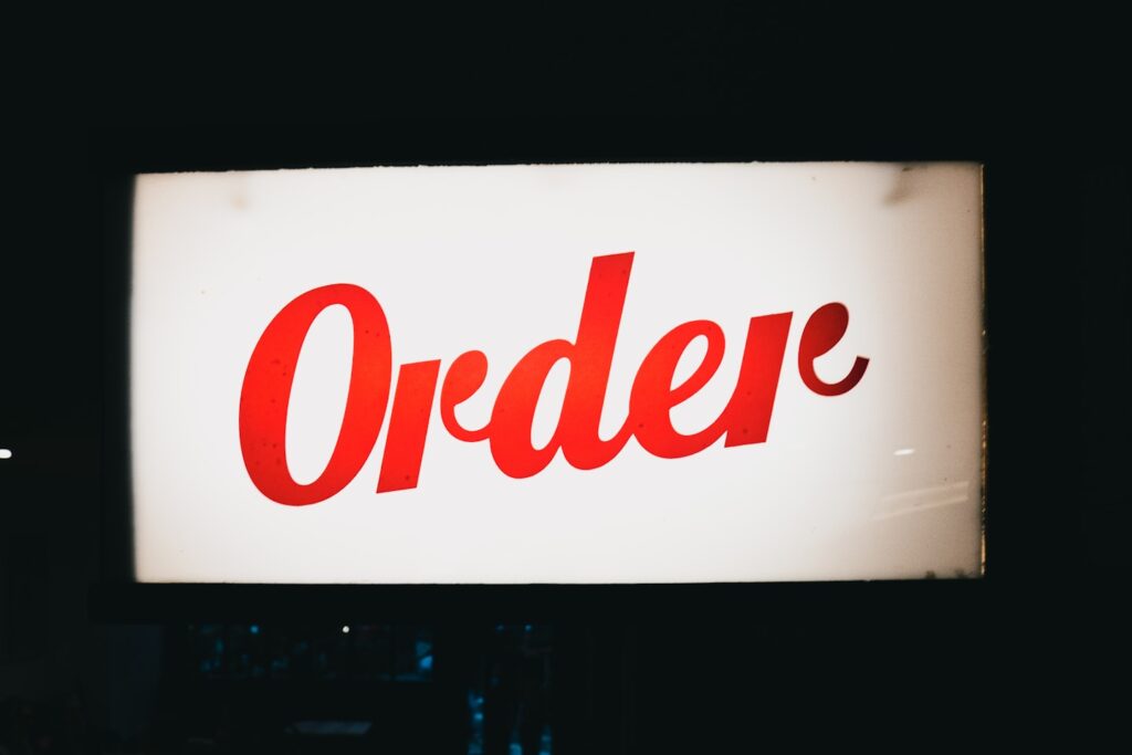 a red order sign hanging from the side of a building